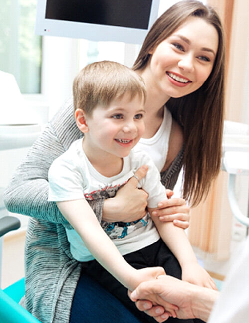 A mother and her child shaking hands with the dentist during a checkup