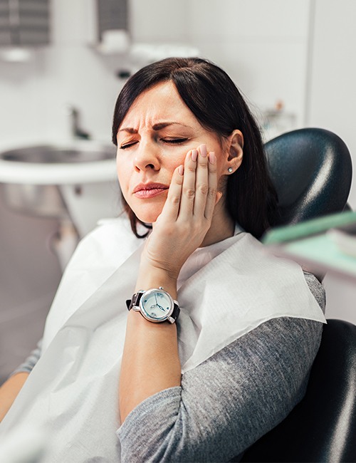 Woman in need of root canal therapy holding jaw