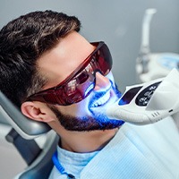 Man with dark hair having teeth whitened at the dental office