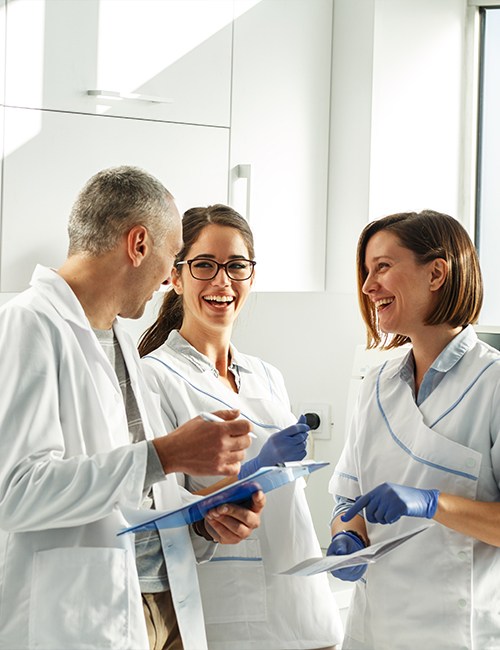 Three dentists reviewing dental patient chart