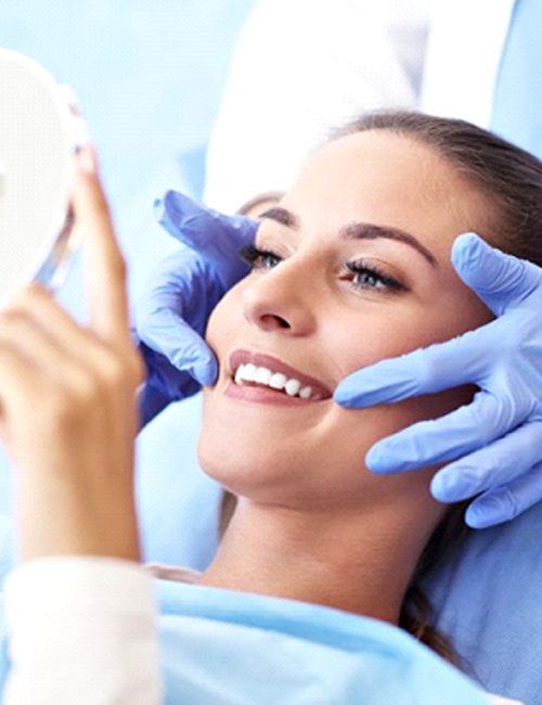 dental patient admiring her new smile in a mirror