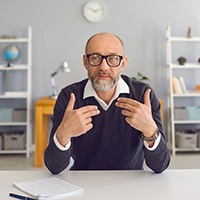 An older man speaking with someone across the table