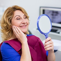 A cheerful mature woman looking at her smile in a hand mirror