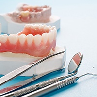 A close-up of a complete denture against a blue background