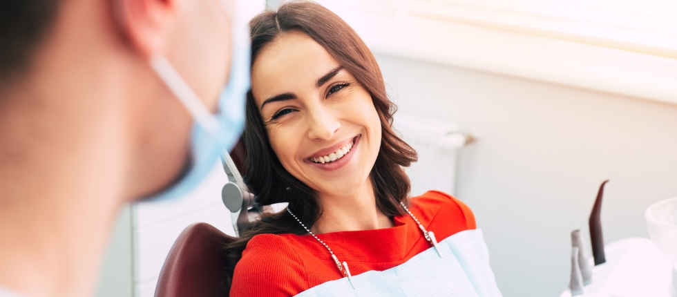 Woman in dental chair laughing with dentist