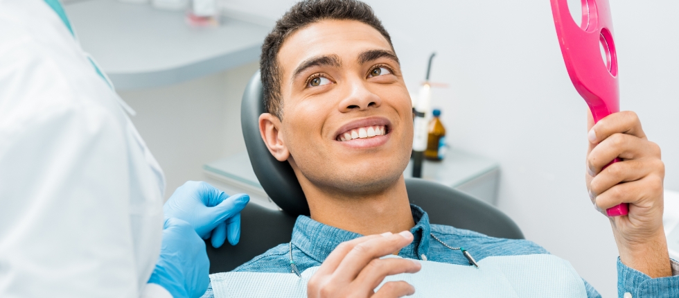 Dentist talking to smiling man in dental chair