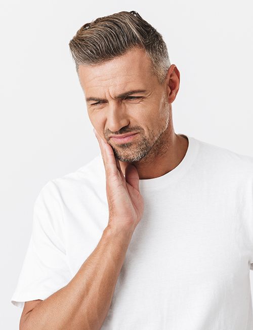 Man in need of tooth extractions holding his jaw