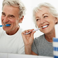 a couple brushing their teeth for dental implant care