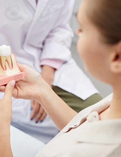 a dentist showing a patient a model of dental implants