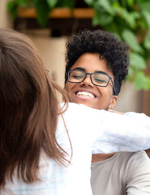 woman smiling and hugging a friend