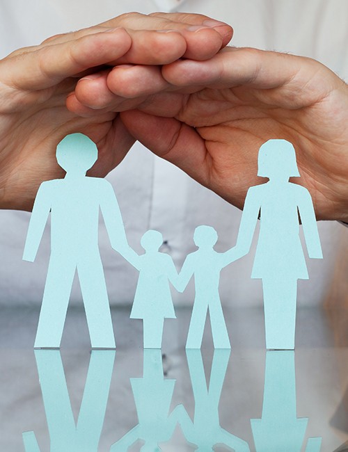 Hands covering paper cut out of family holding hands