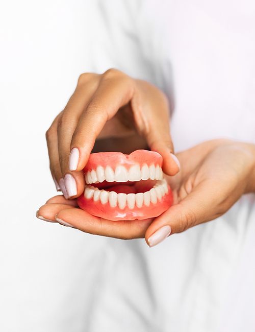 Hand holding full set of dentures