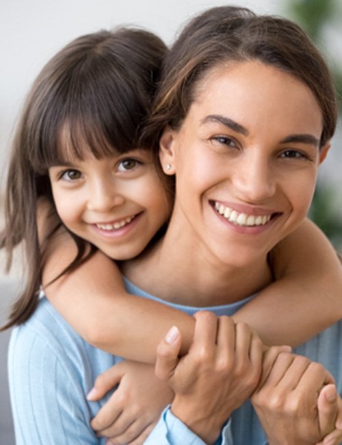 Daughter hugging mom from behind on couch