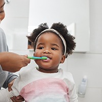 Woman brushing an adorable toddler’s teeth