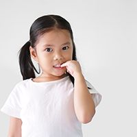 Girl in white t-shirt nibbling her fingernails