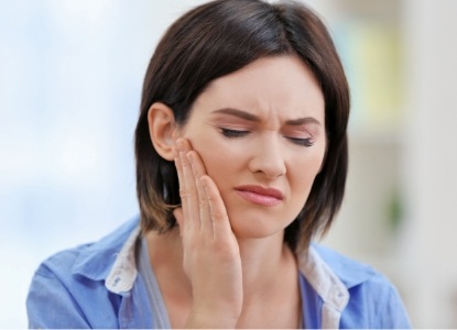 Woman in need of emergency dentistry holding jaw in pain