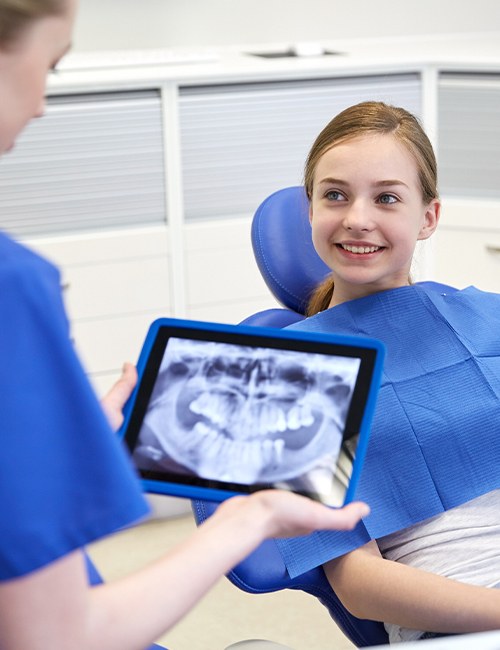Dentist looking at young patient's digital x-rays on tablet computer