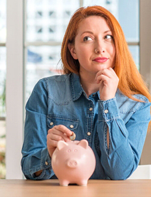 woman putting a coin into a piggy bank