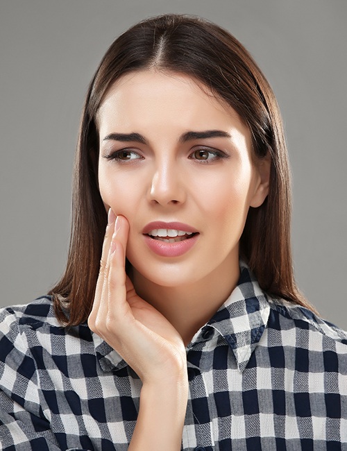 Woman in need of wisdom tooth extraction holding cheek