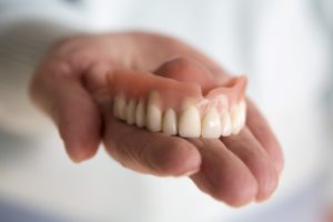 Hand holding denture