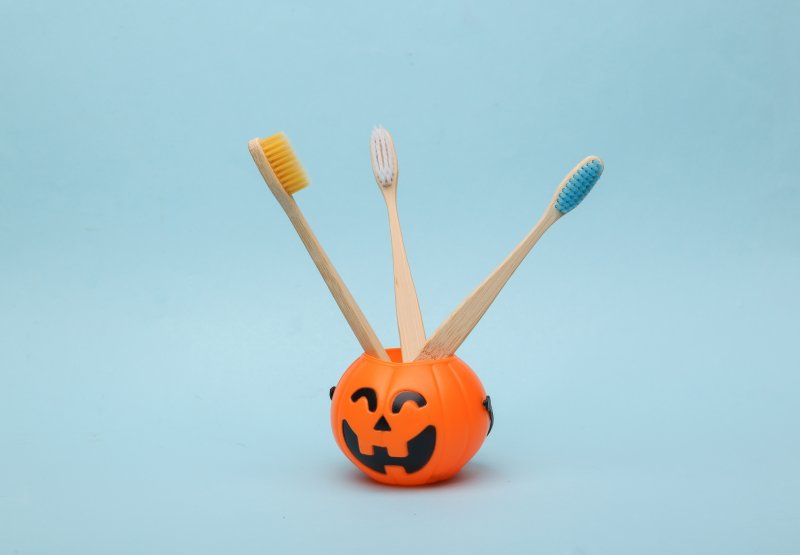 Toothbrushes in a Jack-o-Lantern holder, symbolizing Halloween oral health tips