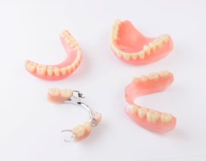 Various types of dentures arranged in a circle on a white background
