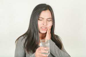 Woman holding a glass of water experiencing dental pain