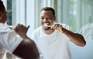 Man in white shirt brushing his teeth