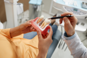 a patient and dentist looking at a model of a dental implant